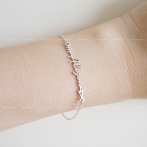 May include: A silver bracelet with a delicate chain and an arrow charm with the name "Alison" written in cursive.