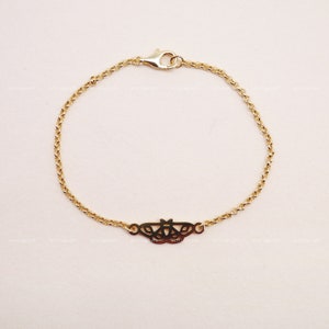 Könnte beinhalten: Ein zartes goldenes Kettenarmband mit einem zarten Schmetterlingsanhänger. Die Kette ist ein schlichtes, verlinktes Design.