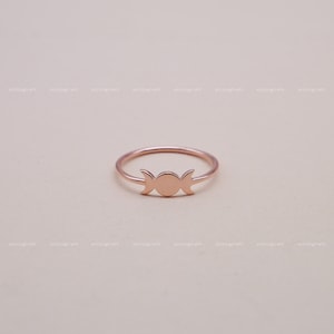 May include: A rose gold ring with a triple moon design. The ring is simple and delicate, making it a perfect everyday accessory.