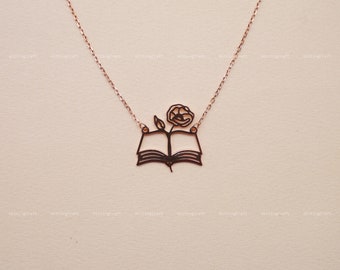 Op de afbeelding: Een ketting van roségoud met een delicate opengewerkte hanger met een boek met een bloem die eruit groeit.