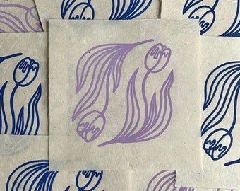 May include: Six cards with a simple floral design printed on them. The cards are made of a textured paper and feature a purple tulip design on a beige background. The design is repeated on each card, but the orientation of the tulips is different.