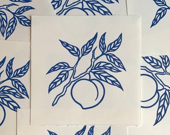 May include: A blue and white print of a peach tree branch with leaves and a single peach. The print is on a white background.