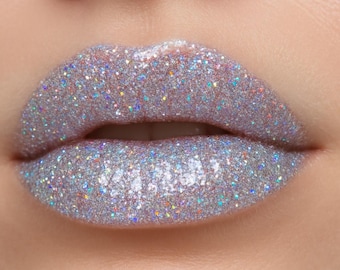 May include: Close-up of a person's lips with silver glitter makeup. The glitter is iridescent and reflects light.