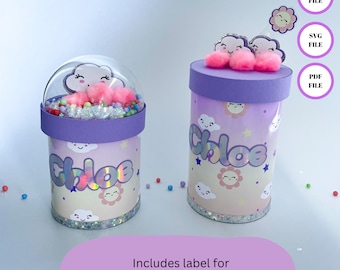 Könnte beinhalten: Zwei personalisierte Geschenkboxen in Lila und Rosa mit einem Wolken- und Sonnenmotiv. Die Boxen sind mit dem Namen "Chloe" verziert und beinhalten ein Etikett für 1,4 oz und 2,5 oz Dosen. Das Design beinhaltet eine Wolke mit einem lächelnden Gesicht, einen rosa Pompon und eine gelbe Sonne.