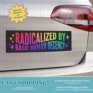 May include: A black rectangular bumper sticker with the text "RADICALIZED BY BASIC HUMAN DECENCY" in rainbow colors. The sticker is affixed to the back of a silver car. A yellow sticker with the words "Choose Sticker or Magnet" is also visible.