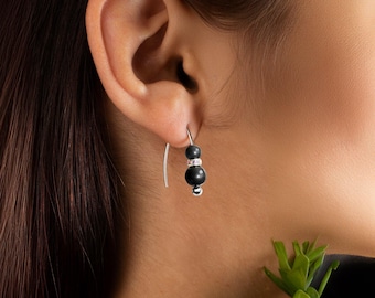 May include: A pair of silver dangle earrings with black beads and a clear rhinestone accent.