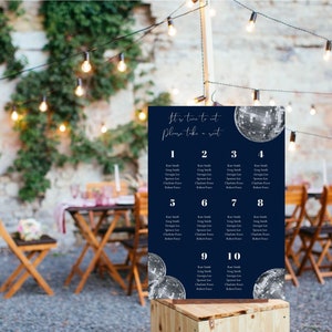May include: A navy blue seating chart with silver glitter disco balls. The chart has the text "It's time to eat, Please take a seat." and lists table numbers 1 through 10 with guest names.
