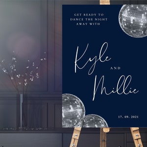 May include: A navy blue wedding welcome sign with white text that reads "Get ready to dance the night away with Kyle and Millie 17.09.2021". The sign features silver disco balls.