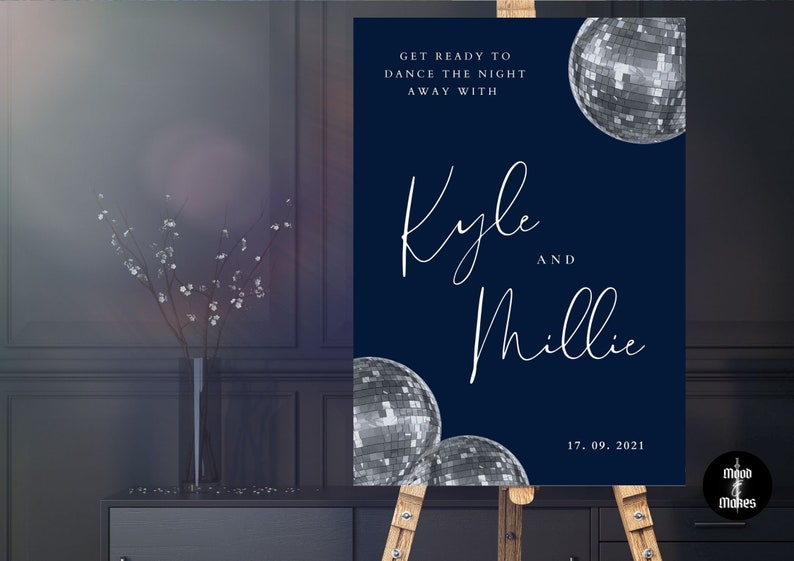 May include: A navy blue wedding welcome sign with white text that reads "Get ready to dance the night away with Kyle and Millie 17.09.2021". The sign features silver disco balls.