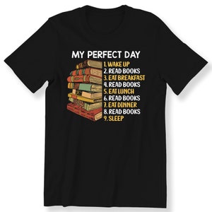 May include: Black t-shirt featuring a stack of books and the text "My Perfect Day" with a list of activities including "Read Books" multiple times.