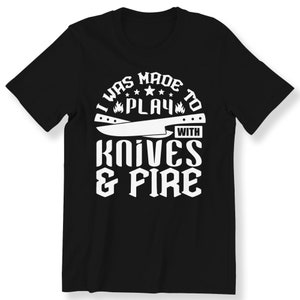 May include: Black t-shirt with white text that reads "I was made to play with knives & fire".