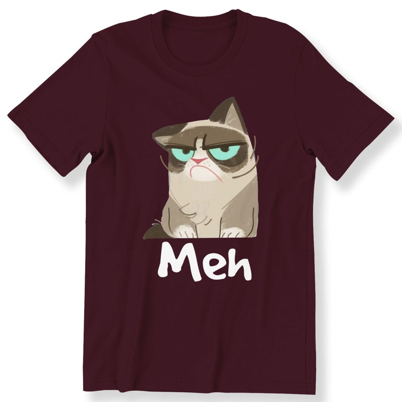 May include: A maroon t-shirt featuring a cartoon image of a grumpy cat with the word "Meh" printed beneath it.