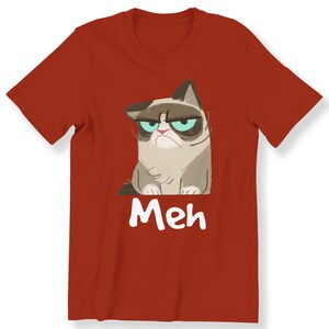 May include: Red t-shirt featuring a cartoon image of a grumpy cat with the word "Meh" printed beneath it.