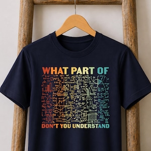 May include: A navy blue short-sleeved t-shirt featuring a colourful graphic print of various mathematical equations and formulas. The text "WHAT PART OF" is printed in orange above the math, and "DON'T YOU UNDERSTAND" is printed in blue below.