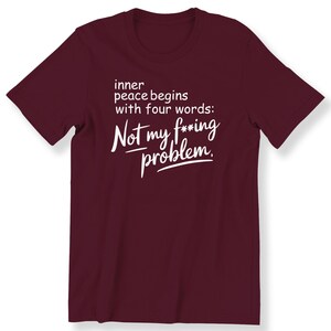 Op de afbeelding: Bordeaux T-shirt met witte tekst die luidt: "inner peace begins with four words: Not my f***ing problem."