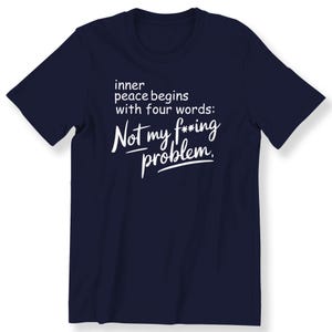 Op de afbeelding: Donkerblauw T-shirt met witte tekst die luidt: "inner peace begins with four words: Not my f***ing problem."