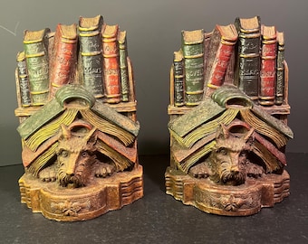May include: A pair of bookends featuring a brown and black terrier dog with a book stack behind it. The books have titles like "Novels", "Poetry", "Essays", and "History".
