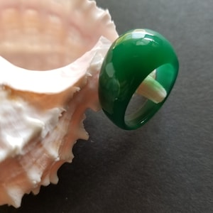 May include: A green jade ring with a smooth, polished finish. The ring is thick and has a rounded shape.