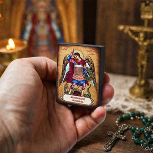 Op de afbeelding: Een klein rechthoekig houten bordje met een kleurrijke illustratie van aartsengel Michaël die een slang verslaat. De tekst luidt Saint Michael bovenaan en Archangel Michael op een wit lint onderaan de afbeelding.