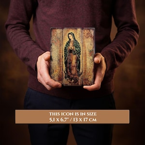 Pode incluir: &Iacute;cone religioso retratando uma figura em vestes e v&eacute;u escuros, com aur&eacute;ola, segurado por uma pessoa. O &iacute;cone mede 13 x 17 cm. O fundo tem uma apar&ecirc;ncia vintage e envelhecida com um brilho dourado.