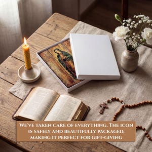 Pode incluir: Um &iacute;cone religioso da Virgem Maria &eacute; exibido em uma caixa branca aberta. Uma vela acesa, um livro aberto, um ros&aacute;rio e um pequeno vaso de flores brancas est&atilde;o em uma mesa de madeira. O texto diz: WE'VE TAKEN CARE OF EVERYTHING. THE ICON IS SAFELY AND BEAUTIFULLY PACKAGED, MAKING IT PERFECT FOR GIFT-GIVING