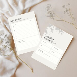 Peut inclure: Deux feuilles de papier blanc cass&eacute; avec du texte noir. Une feuille est intitul&eacute;e Coaching Session Notes avec des champs pour le nom du client, la date, le num&eacute;ro de session, la dur&eacute;e et l'objectif. L'autre est intitul&eacute;e Agreed Actions avec une liste num&eacute;rot&eacute;e.