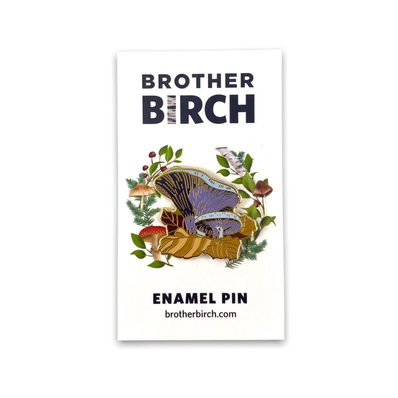 May include: Enamel pin featuring a purple and gold mushroom with a blue and white pattern. The mushroom is surrounded by leaves, berries, and birch bark. The pin is labelled "Brother Birch Enamel Pin" and "brotherbirch.com".