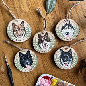 Puede incluir: Cinco adornos de madera con retratos pintados de perros. Cada adorno tiene un borde de hojas verdes y el nombre del perro est&aacute; escrito debajo del retrato. Los nombres son Pumba, Finley, Sydra, Nadia y Pepper.
