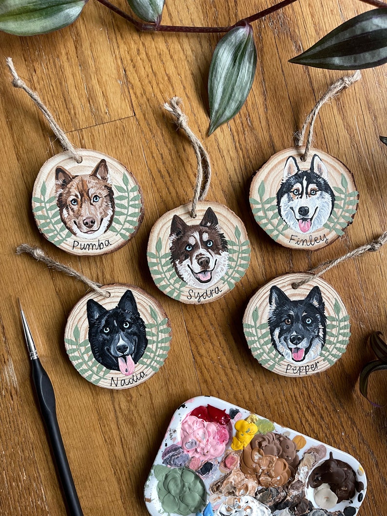 Puede incluir: Cinco adornos de madera con retratos pintados de perros. Cada adorno tiene un borde de hojas verdes y el nombre del perro est&aacute; escrito debajo del retrato. Los nombres son Pumba, Finley, Sydra, Nadia y Pepper.