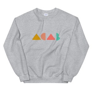 K&ouml;nnte beinhalten: Ein hellgraues Sweatshirt mit dem Wort "ACAB" in bunten geometrischen Formen. Die Buchstaben sind in Orange, Pfirsich, Koralle und T&uuml;rkis gehalten. Das Sweatshirt ist aus einem weichen Material.