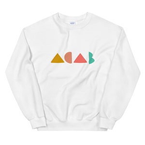 K&ouml;nnte beinhalten: Wei&szlig;es Sweatshirt mit dem Wort "ACAB" in bunten geometrischen Formen. Die Buchstaben bestehen aus einem senfgelben Dreieck, einem pfirsichfarbenen Halbkreis, einem korallenfarbenen Dreieck und einem t&uuml;rkisfarbenen Halbkreis.
