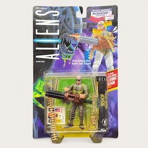 May include: An Aliens Bishop action figure in original packaging. The figure wears a green vest and brown pants, holding a large black gatling gun with a gold ammunition belt. The card features the text Aliens, Space Marine Bishop Android, and Desert Storm.
