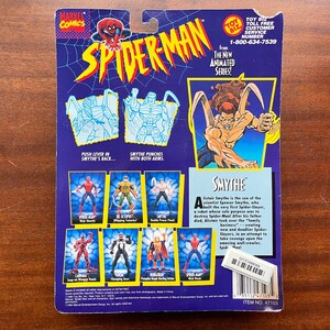 May include: A blue and purple action figure card featuring Spider-Man and the villain Smythe. The card has a picture of Smythe with his arms outstretched and a description of his character. The card also shows different action poses for Spider-Man and Smythe.