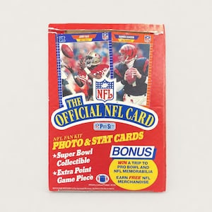 May include: A red rectangular box for The Official NFL Card Pro Set fan kit. The front features images of football players, the NFL logo, and text including Photo & Stat Cards, Super Bowl Collectible, and a bonus offer to win a trip.