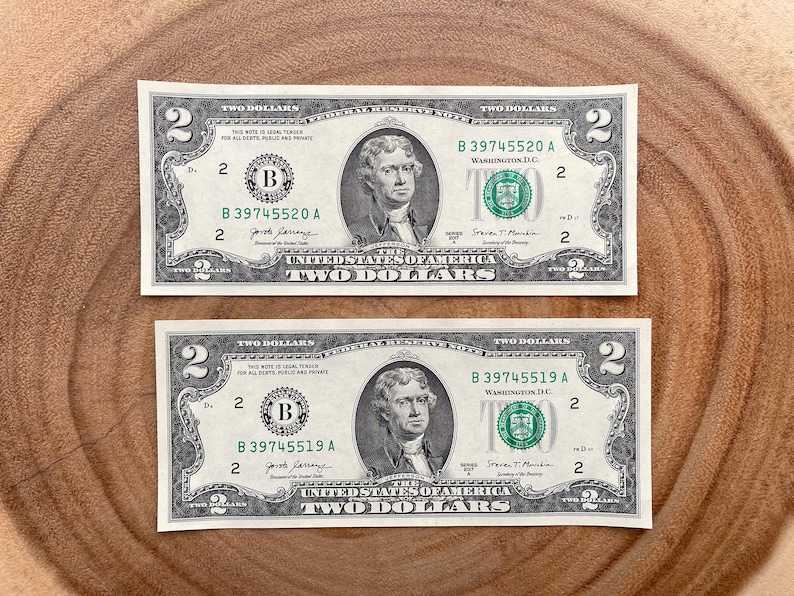 May include: Two $2 bills with the portrait of Thomas Jefferson on them. The serial numbers are B 39745520 A and B 39745519 A.
