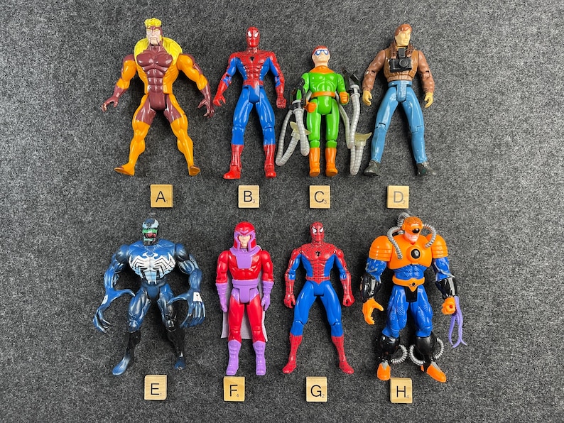 Selection of loose 1990s Toy Biz Spiderman and X Men action figures arranged on gray background with lettered markers