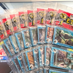 May include: A collection of 42 E.T. the Extra-Terrestrial movie photo cards, sealed in clear plastic. The cards have blue borders and feature images from the film. The packaging includes the text "42 Movie Photo Cards E.T. The Extra-Terrestrial".