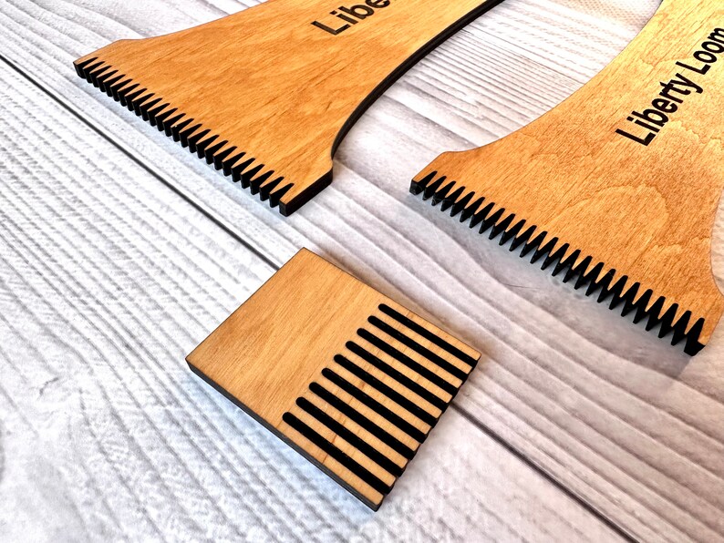 May include: A set of three wooden weaving looms with black teeth. The looms are labeled "Liberty Loom".