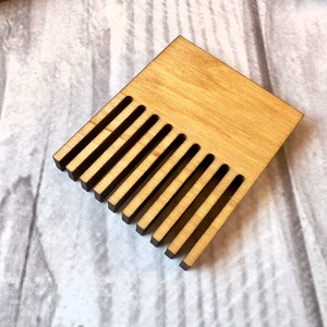 May include: A wooden comb with 12 teeth, made of light brown wood with a natural finish.