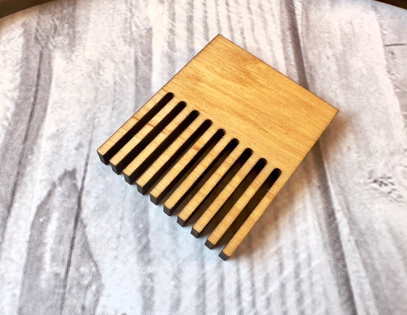 May include: A wooden comb with 12 teeth, made of light brown wood with a natural finish.