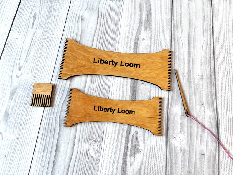 May include: Two wooden looms with the text "Liberty Loom" printed on them. A small wooden comb and a pink yarn with a needle are also included.