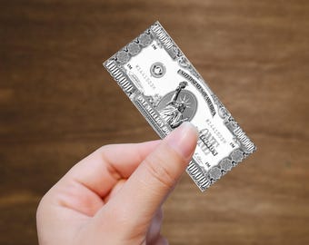 May include: A novelty one million dollar bill held in a hand. The bill features the Statue of Liberty and the text "ONE MILLION DOLLARS". The bill is white with black details and a decorative border.