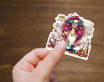 Op de afbeelding: Een sticker met een kleurrijke illustratie van een vrouw met roze en paars haar, die een ronde blauwe zonnebril en een witte schort draagt, en een pot met eten roert in een keukensituatie.