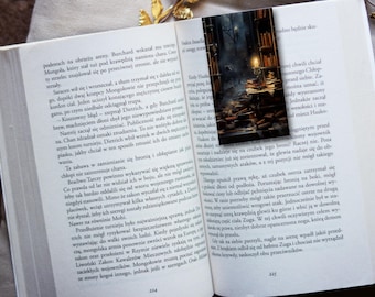 Op de afbeelding: Een close-up van een boek met een bladwijzer met een donkere, mysterieuze bibliotheekscène. De bladwijzer is gemaakt van dik karton en heeft een matte afwerking. Het boek is open op een pagina met tekst in het Pools.