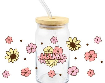 May include: A clear glass jar with a wooden lid and a straw. The jar features a floral design with the word "MAMA" in pink and yellow lettering. The jar is surrounded by pink and yellow flowers.