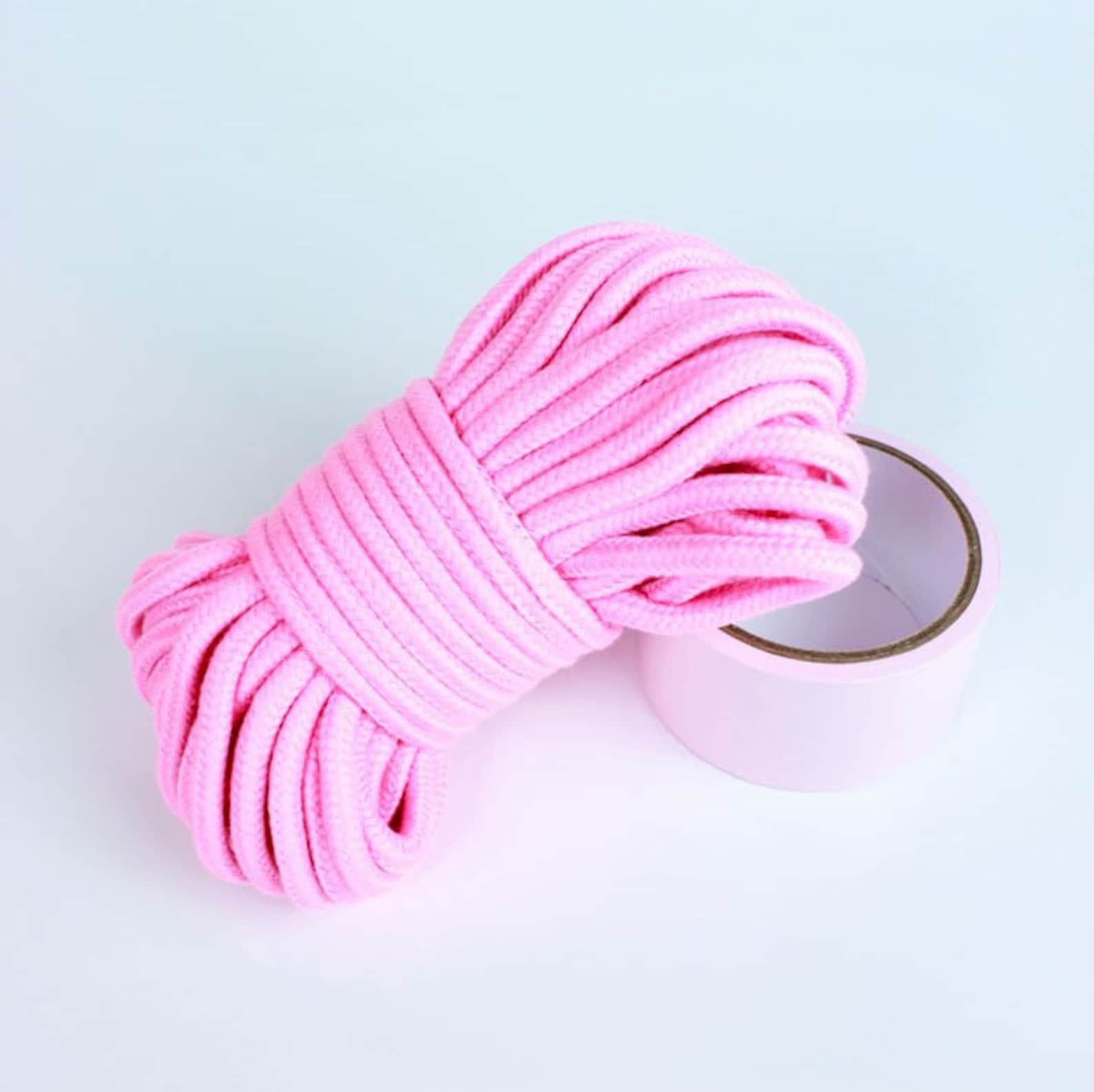Pink cotton bondage rope and PVC tape coiled together for beginner BDSM ties and cute bondage restraint options.