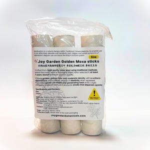Puede incluir: Un paquete de barritas de moxa doradas Joy Garden. La etiqueta incluye texto en inglés y chino, que describe el producto como una terapia de medicina tradicional china. Las barritas de moxa son cilíndricas y de color beige.