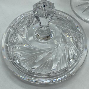 May include: A clear glass lid with a crystal knob and a swirl pattern. The lid is designed for a serving dish or bowl.