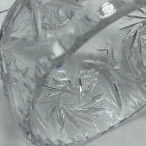 May include: A clear glass bowl with a starburst pattern etched into the bottom. The bowl is made of crystal and has a delicate, elegant design.
