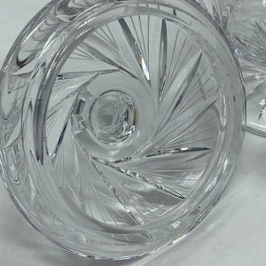 May include: Close-up of the underside of a clear glass bowl with a cut glass design. The bowl has a wide, flat base and a deep, round centre.